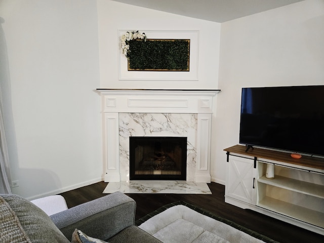 living room with dark hardwood / wood-style floors, vaulted ceiling, and a premium fireplace