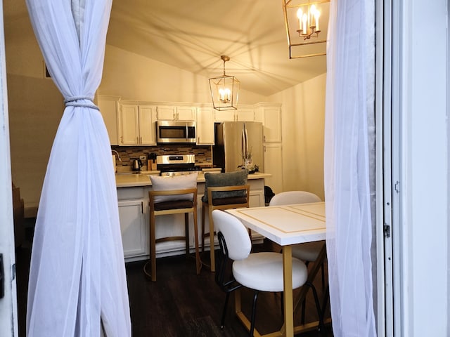 dining space featuring a chandelier, dark hardwood / wood-style floors, and vaulted ceiling