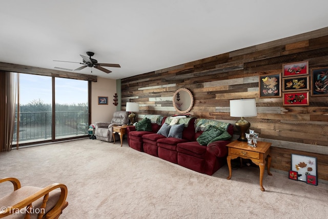 carpeted living room with ceiling fan and wooden walls