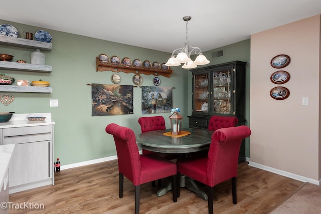 dining room with hardwood / wood-style floors and a notable chandelier