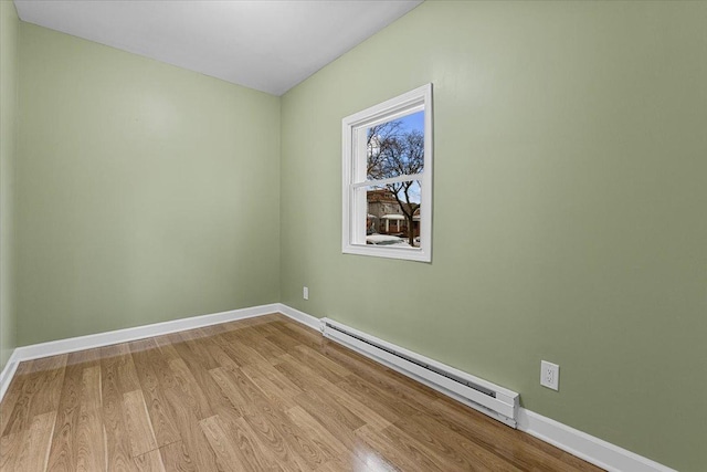 unfurnished room featuring light hardwood / wood-style floors and a baseboard heating unit