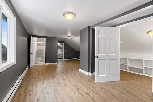 bonus room with built in shelves, light wood-type flooring, baseboard heating, and lofted ceiling