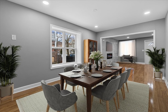 dining room featuring a high end fireplace and wood-type flooring