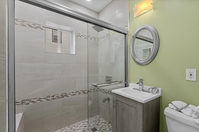 bathroom with an enclosed shower, vanity, and toilet