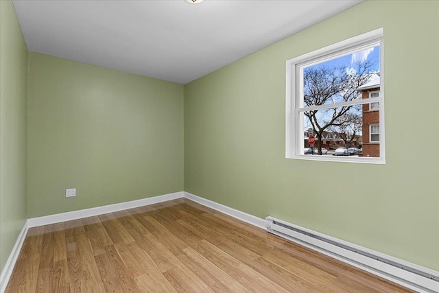 unfurnished room featuring wood-type flooring and baseboard heating