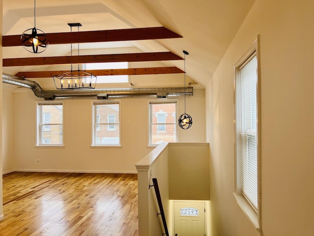 interior space featuring a chandelier, plenty of natural light, lofted ceiling with beams, and light wood-type flooring