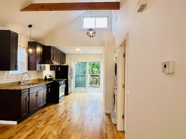 kitchen featuring gas stove, sink, a healthy amount of sunlight, and stacked washer and dryer