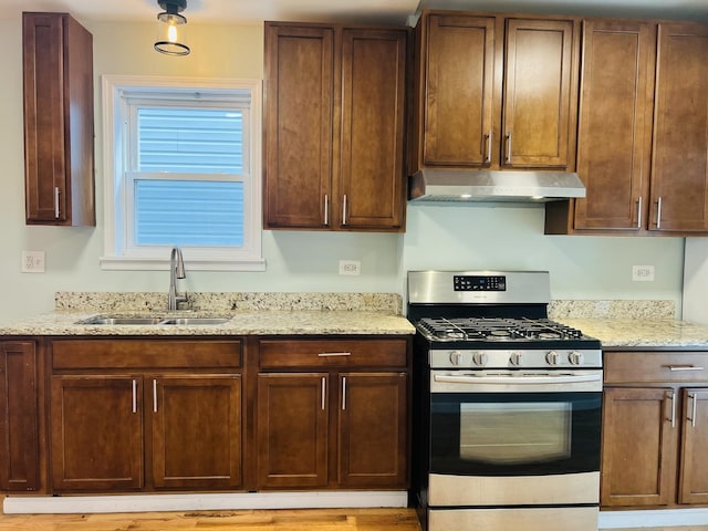 kitchen featuring light stone counters, stainless steel range with gas cooktop, and sink