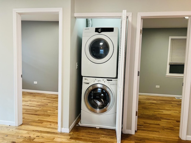 laundry room featuring hardwood / wood-style flooring and stacked washer / dryer