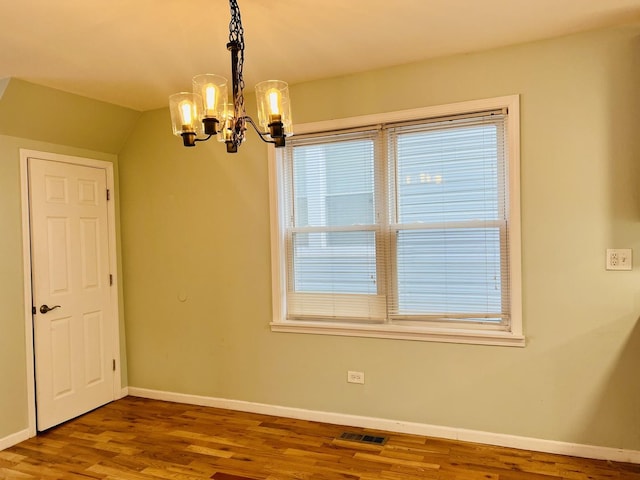 unfurnished room featuring a chandelier and wood-type flooring