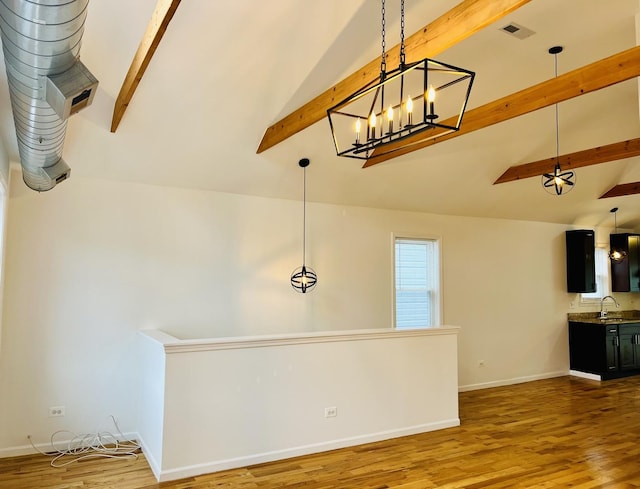 unfurnished living room featuring hardwood / wood-style floors, beamed ceiling, and sink