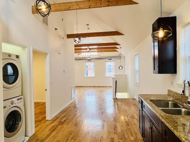 kitchen with stacked washer and dryer, beamed ceiling, hanging light fixtures, and high vaulted ceiling