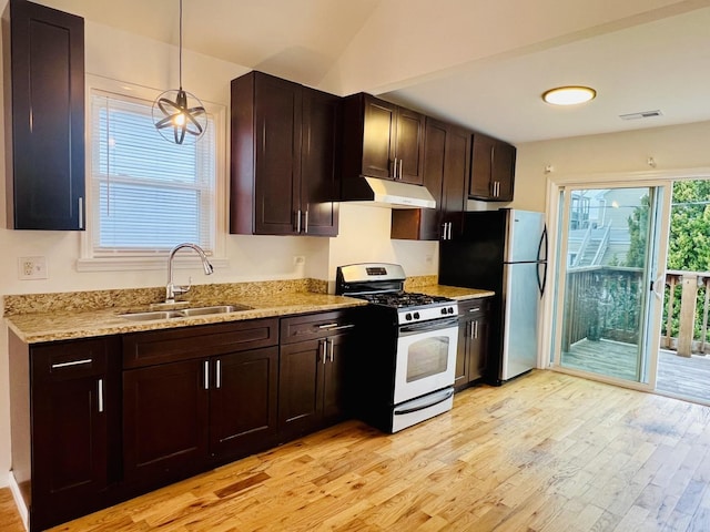 kitchen featuring pendant lighting, sink, light hardwood / wood-style flooring, white gas range, and stainless steel refrigerator