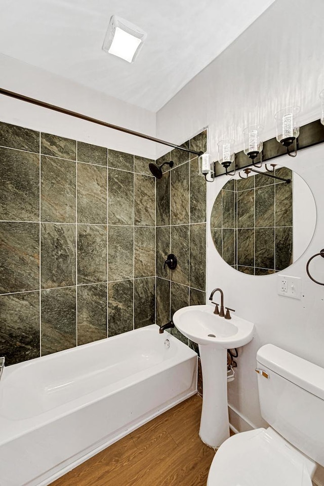 bathroom featuring toilet, wood-type flooring, and tiled shower / bath