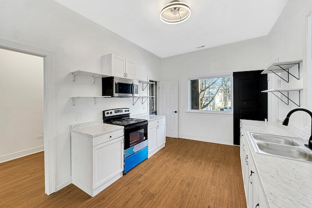 kitchen with range with electric cooktop, light hardwood / wood-style floors, white cabinetry, and sink