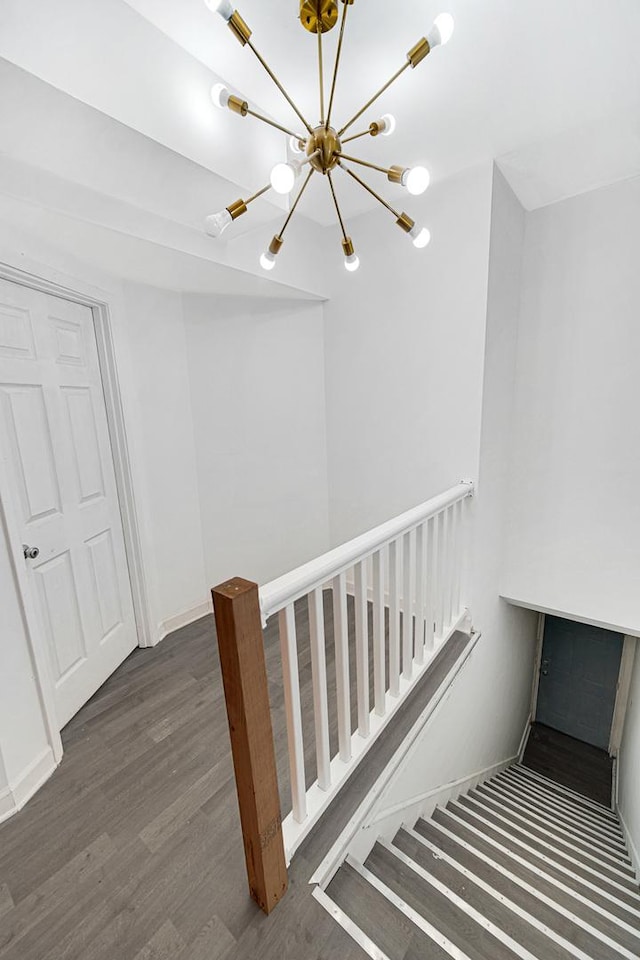 stairs with hardwood / wood-style floors and an inviting chandelier