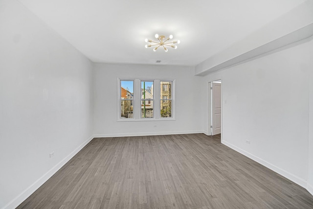 empty room featuring hardwood / wood-style floors and an inviting chandelier