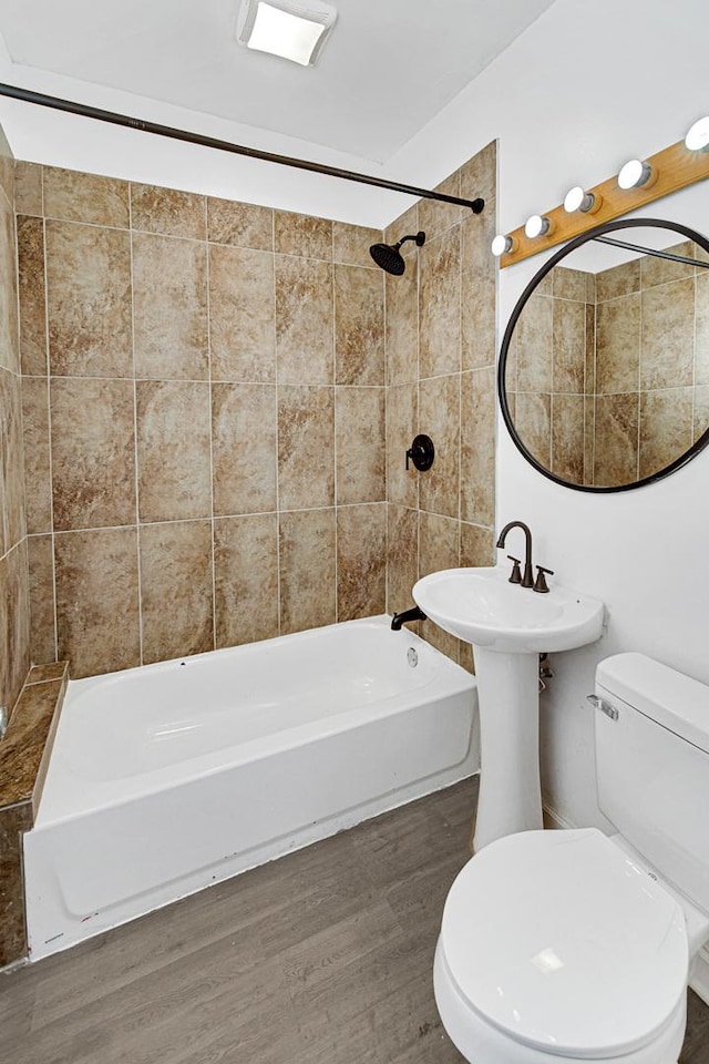 bathroom featuring tiled shower / bath combo, hardwood / wood-style flooring, and toilet