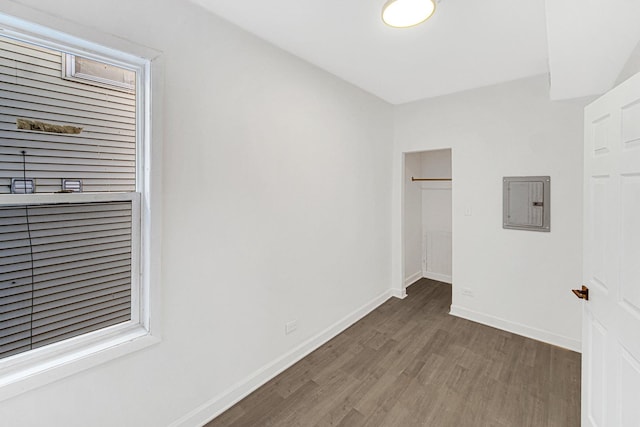 unfurnished bedroom with a walk in closet, dark hardwood / wood-style flooring, electric panel, and a closet