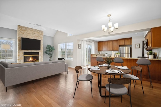 dining area with wood-type flooring, lofted ceiling, a notable chandelier, and a fireplace