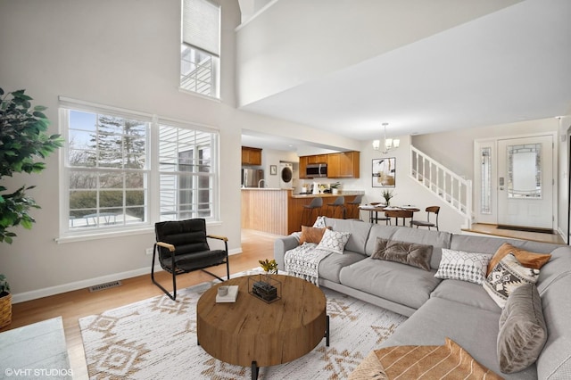 living room with an inviting chandelier, a high ceiling, and light wood-type flooring