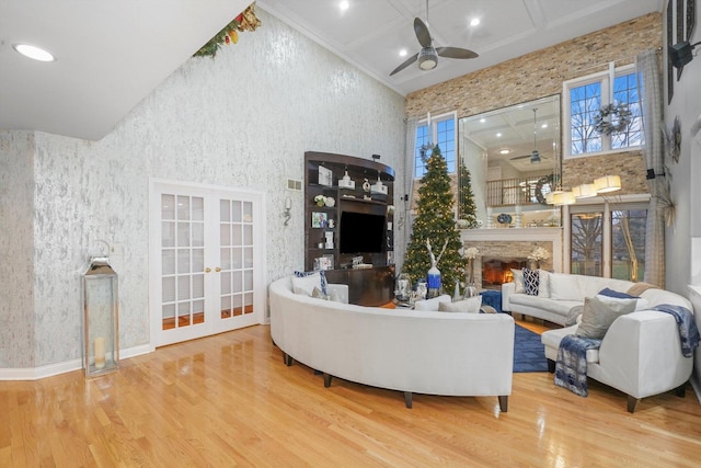 living room with ceiling fan, french doors, a high ceiling, wood-type flooring, and ornamental molding