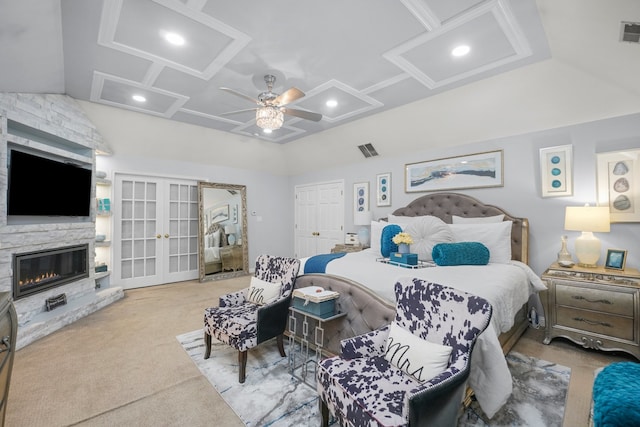 carpeted bedroom with ceiling fan, lofted ceiling, a fireplace, and french doors