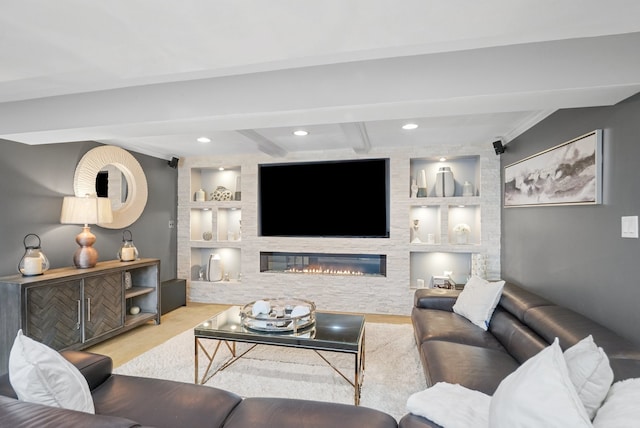 living room with beamed ceiling, built in shelves, a fireplace, and light hardwood / wood-style flooring