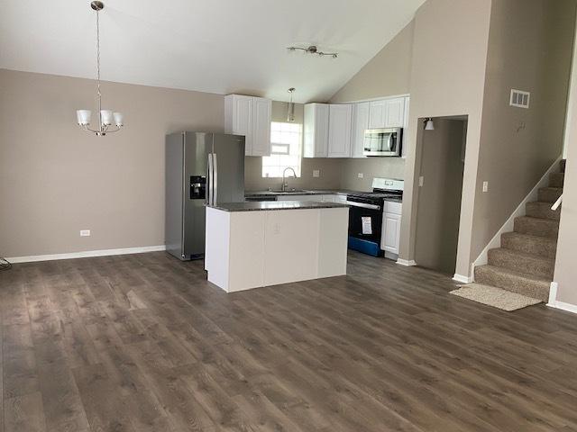 kitchen featuring stainless steel appliances, dark wood-type flooring, pendant lighting, white cabinets, and a kitchen island