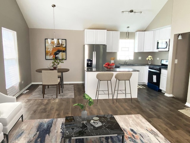 kitchen featuring white cabinets, decorative light fixtures, stainless steel appliances, and vaulted ceiling