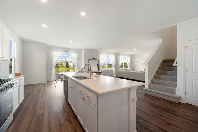 kitchen with dark hardwood / wood-style flooring, stainless steel appliances, sink, a center island with sink, and white cabinets