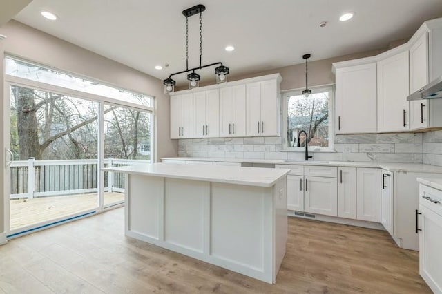 kitchen featuring white cabinetry, light hardwood / wood-style flooring, pendant lighting, and sink