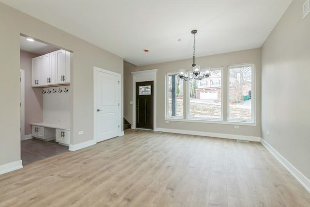 unfurnished dining area featuring an inviting chandelier and light wood-type flooring