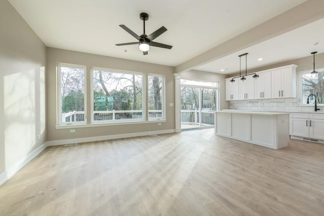 interior space featuring pendant lighting, light hardwood / wood-style flooring, white cabinetry, and plenty of natural light