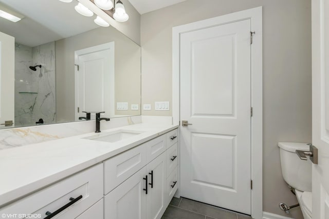 bathroom with a tile shower, tile patterned flooring, vanity, and toilet