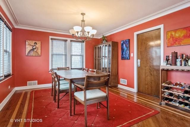 dining area featuring visible vents, a chandelier, crown molding, and wood finished floors