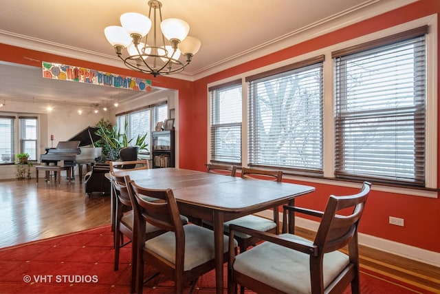 dining area with a wealth of natural light, a notable chandelier, crown molding, and wood finished floors