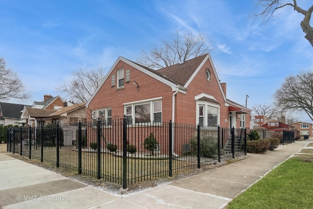 view of side of property featuring brick siding, a fenced front yard, and a shingled roof