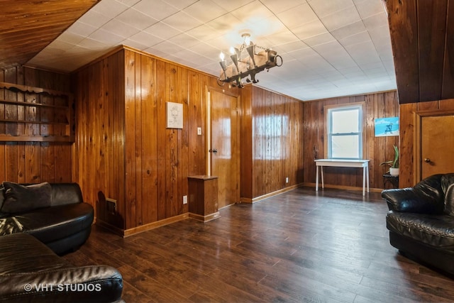 living room featuring an inviting chandelier, baseboards, wood finished floors, and wood walls