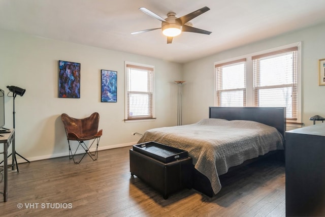 bedroom featuring ceiling fan, multiple windows, baseboards, and wood finished floors