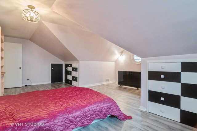 bedroom featuring lofted ceiling, visible vents, baseboards, and wood finished floors