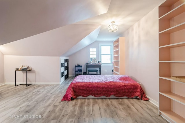 bedroom featuring lofted ceiling, a notable chandelier, baseboards, and wood finished floors