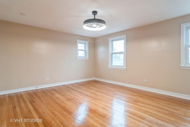 spare room featuring a ceiling fan, light wood-style flooring, and baseboards