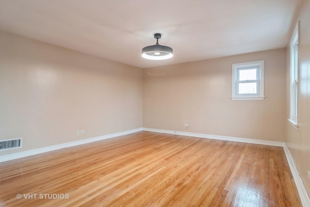 unfurnished room featuring light wood-style flooring, visible vents, and baseboards