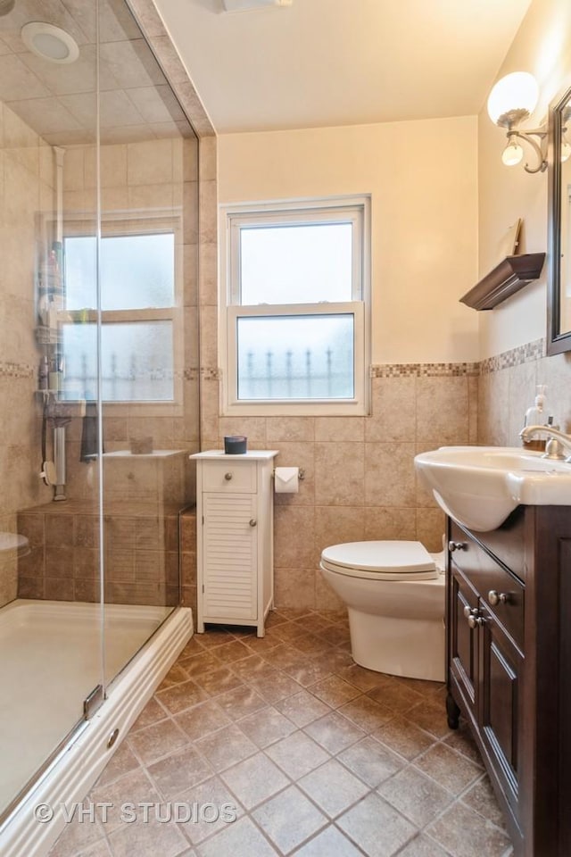 full bathroom with toilet, a stall shower, vanity, and tile walls