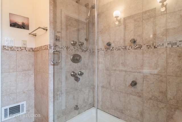 bathroom with a shower stall and visible vents