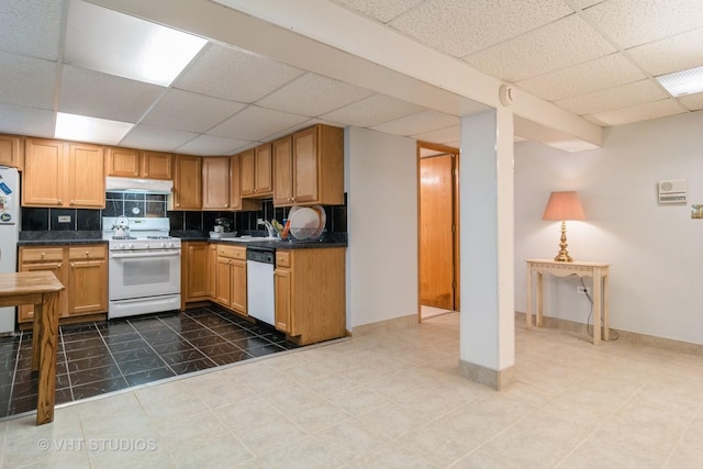 kitchen featuring white appliances, dark countertops, a paneled ceiling, and under cabinet range hood