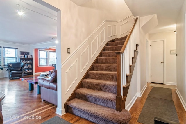 stairs featuring ornamental molding, baseboards, and wood finished floors