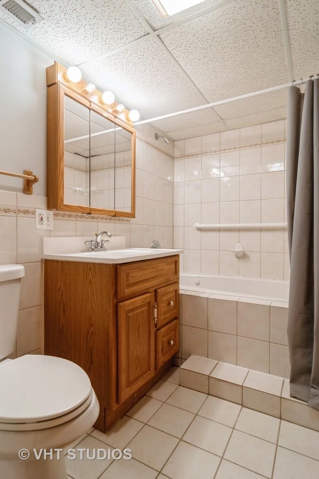 bathroom featuring visible vents, tiled shower / bath combo, tile walls, and toilet