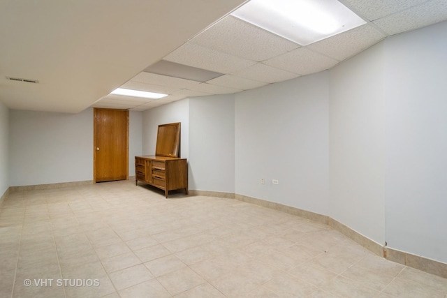 finished below grade area featuring a drop ceiling, visible vents, and baseboards